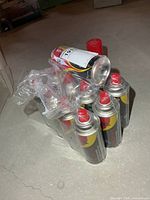 Stack of sealed butane cans with red caps, shrink-wrapped, plus one loose