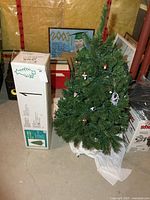4 ft green artificial Christmas tree next to original box and surrounding items