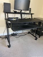 Front view of desk showing upper shelf, main surface, keyboard tray, casters