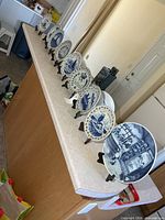 Nine Delft plates arranged on countertop with stands