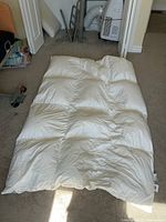Single bed duvet laid flat on floor with wedge pillow visible nearby