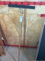 Full view of floor squeegee showing wood handle, metal bracket, rubber blade