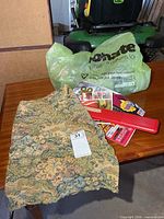 Tabletop view showing bag of yarn, magazines, fabric panel and closed red needle case