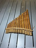 Front view of bamboo pan flute showing fifteen pipes and leaf carvings