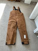 Full view of brown insulated bib overalls laid flat