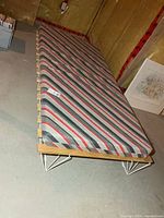 Bed fully assembled showing striped mattress on metal and wood base
