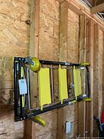 Item folded flat and hung on wall, shows overall design, wheels, yellow steps