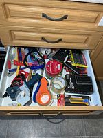 Open drawer showing majority of tools, tapes, pens and batteries