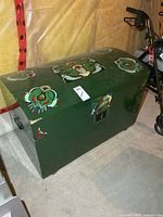 Front and top view of painted green humpback trunk showing decorative motifs and size