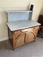 Front view showing marble top, backsplash shelf, brass towel bars and cabinet body