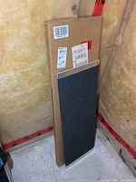 Boxed ramp standing upright beside unboxed ramp showing black grit strips and aluminum surface