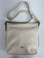 Front view of cream Coach Shay crossbody showing logo, strap and overall condition