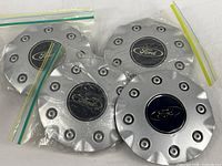 Four identical Ford wheel center caps, three in original plastic