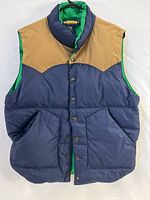 Front view of navy puffer vest with tan yoke and green lining