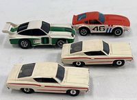 Top view of all four slot cars showing body colors, numbers and missing tire