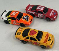 Group view of three Aurora AFX slot cars showing Kodak #4, Motorcraft #15, Tide #5 bodies