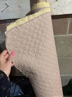 Close view of rolled fabric showing quilted circle pattern and foam backing