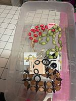 Overview of mixed vintage jewellery items in clear plastic bin