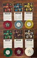 All six colored vinyl singles with sleeves and lyric sheets displayed on wood floor