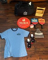 All items laid out: duffel, shirt, sign, paddles, socks, beanie, crate, tape