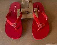 Top view of red Coach flip flops on hanger