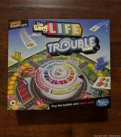 Front of boxed Hasbro Game Mash-ups The Game of Life / Trouble showing title, pop-o-matic bubble graphic, age and player information