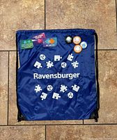 Front view of blue Ravensburger drawstring bag with pins attached