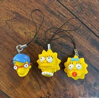 All three Simpsons character keychains displayed on wood surface