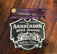 Front view of Sanderson Witch Museum crossbody bag with attached retail tag