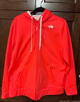 Front view of coral The North Face full-zip hoodie on hanger