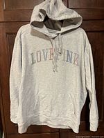 Front view of light gray PINK hoodie with rhinestone LOVE PINK logo and kangaroo pocket