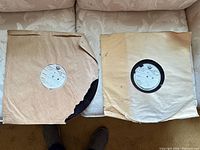 Two 16-inch transcription discs in brown paper sleeves on sofa