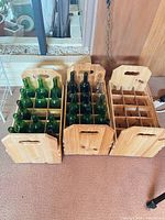 Three wooden wine crates side by side, two filled with green bottles, showing overall design and size