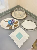Group shot showing crystal bowl, square petal-edge dish, plum motif platter and green-border platter