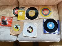 All six 45 RPM records with sleeves plus cleaning cloth and spindle adapters laid out on sofa
