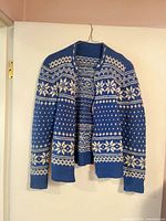 Front view of blue and white Norwegian pattern sweater hanging