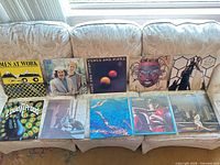 Ten rock LP album covers laid out on sofa