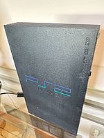 Front and side of Sony PlayStation 2 standing vertically