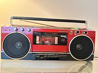 Front view of Sanyo red/black boombox showing speakers, cassette deck, controls, antenna