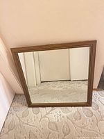Front view of square mirror showing bronze decorative frame and glass