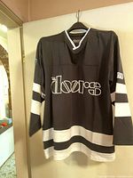 Front view of black and white Doors jersey hanging on door