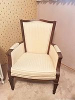 Front view of cream upholstered wood-frame high-back armchair
