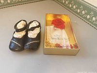 Black baby shoes beside boxed lace handkerchief