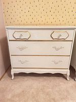 Front view showing two drawers, gold trim, ornate pulls, cabriole legs