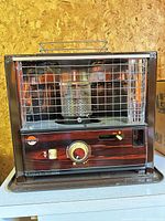 Front view showing faux wood-grain panel, control knob, safety grill, and branding