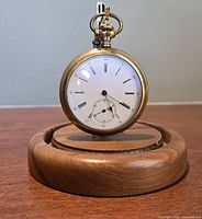 Front view of gold-filled pocket watch on wooden stand