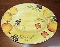 Top view of round yellow platter with fruit and floral painting