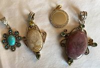 Four costume jewelry pendants laid on white cloth