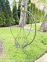 Full view of arched metal hanger with basket outdoors