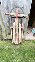 Full view of wooden sled standing against wall